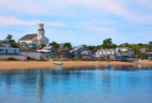 Provincetown buildings and a beach in front of a calm blue bay.