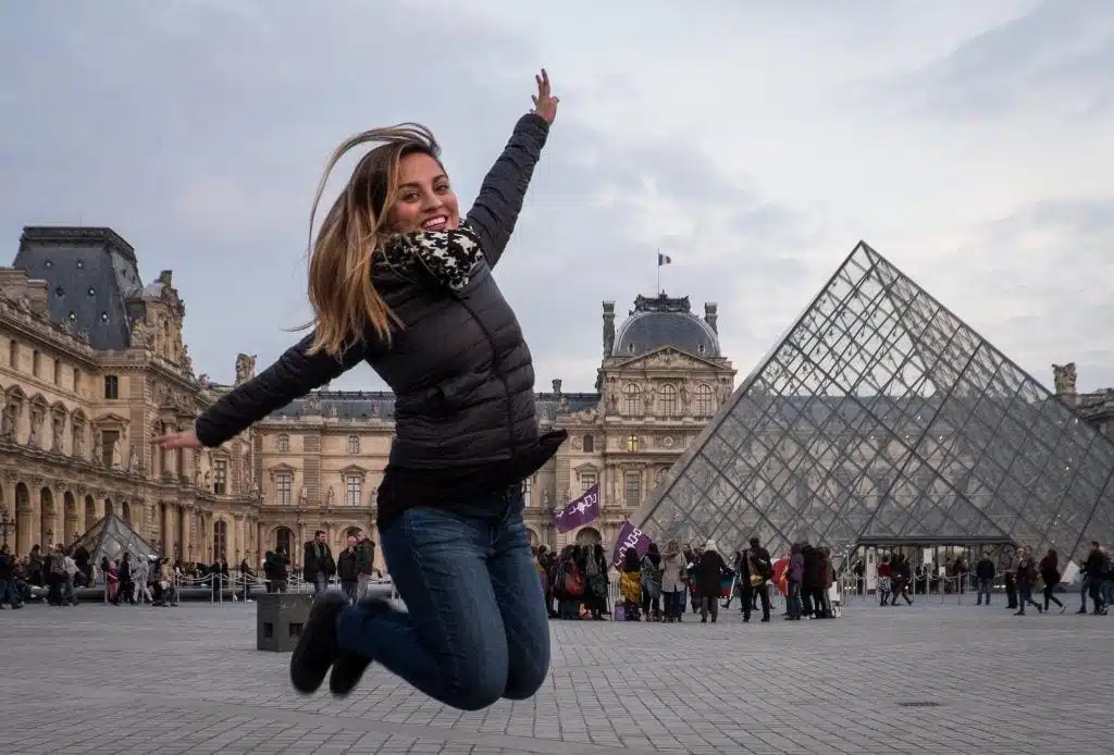 Kate saltó en el aire frente al Museo del Louvre en París y su pirámide de cristal, con las rodillas dobladas debajo de ella.