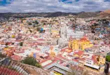 A view of Guanajuato from above, showing thousands of block-shaped buildings in bright colors among the mountains.
