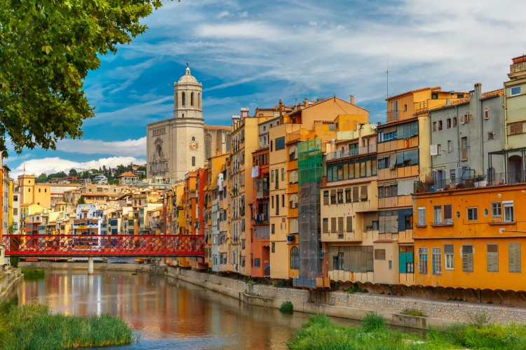Coloridas casas amarillas y naranjas y puente Eiffel, viejos puestos de pescado, reflejados en el agua del río Onyar, en Girona, Cataluña, España.  Catedral de Santa María al fondo.