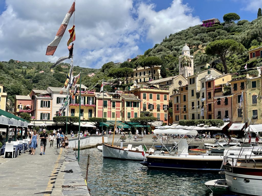 A small Italian seaside village with. big boats clustered in the harbor.