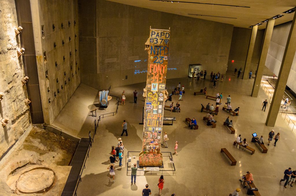 People standing around a concrete block with NYPD and FDNY 343 painted on it at the 9/11 Museum.