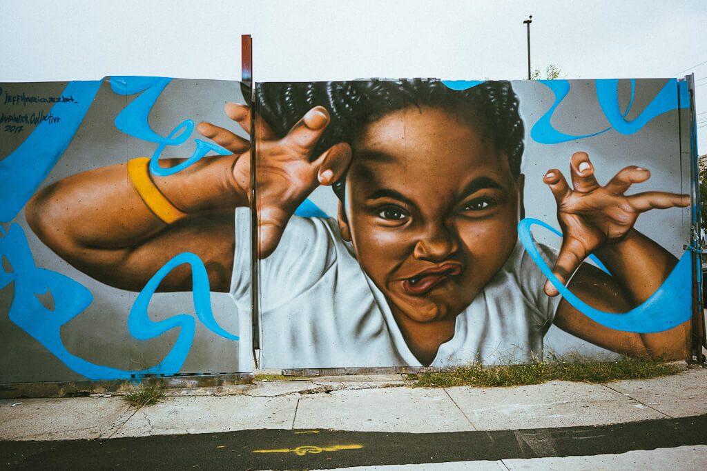A mural of an African American girl with her hands reaching out of the mural