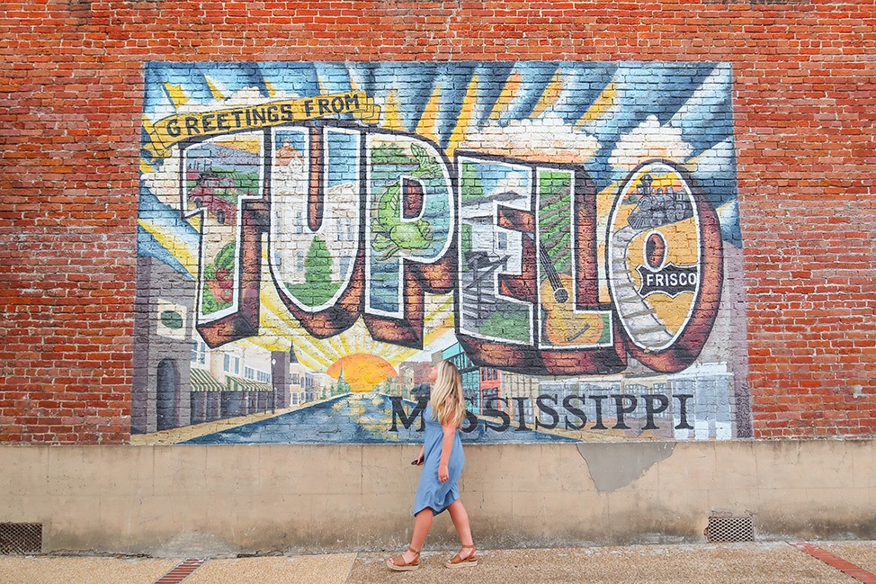 Alex frente al mural de postales de Tupelo