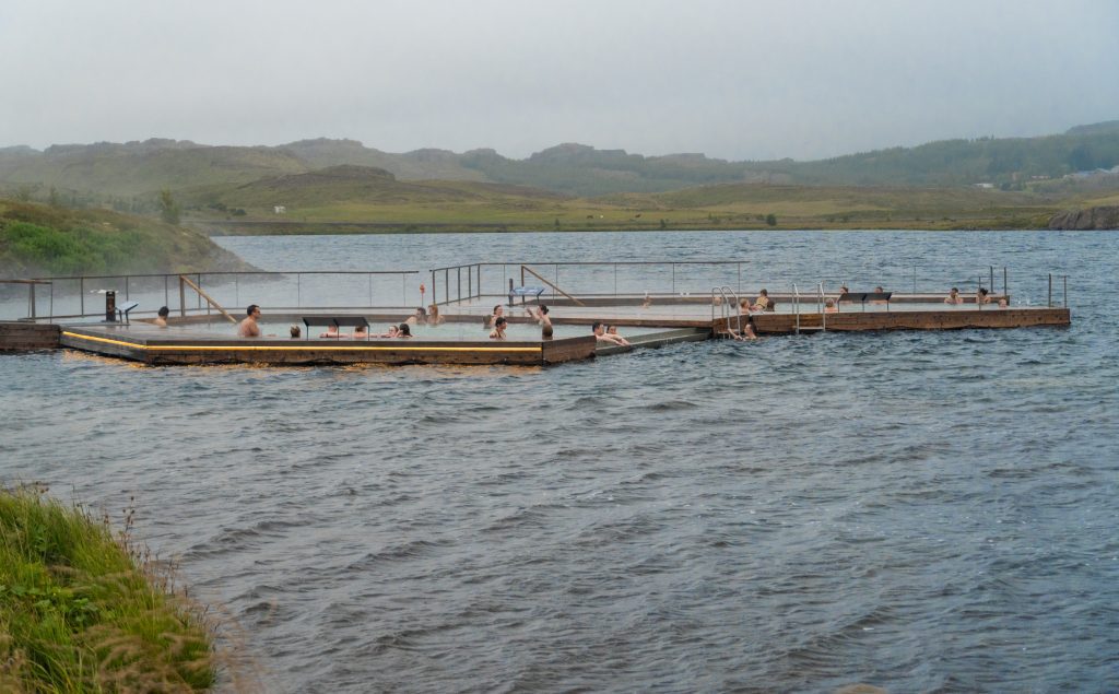 Two hot water pools submerged in a cold lake, several people luxuriating in the warm water.