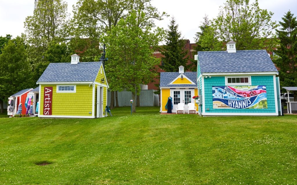 Brightly painted artists' cottages on a lawn.