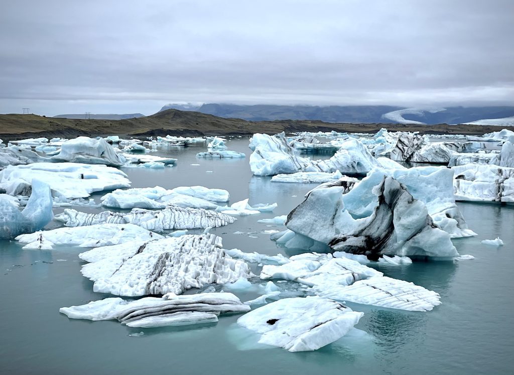 Una laguna todavía gris llena de trozos de hielo flotante.