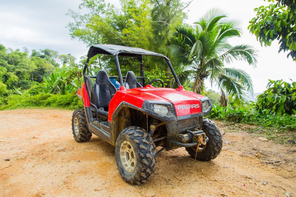 An ATV parked in the jungle on the edge of a cliff.