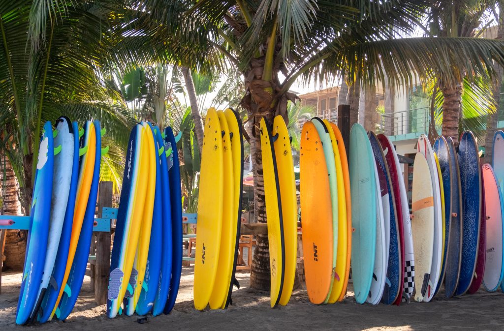 A line of colorful surfboards against palm trees.