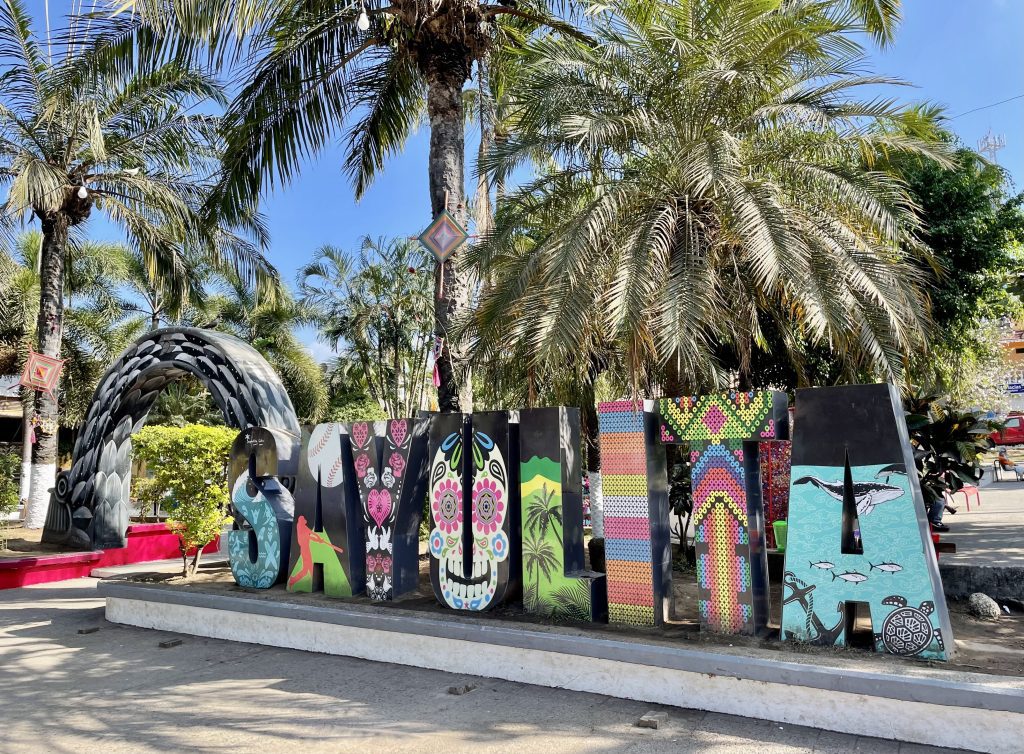 Giant colorful letters spelling out SAYULITA beneath palm trees.