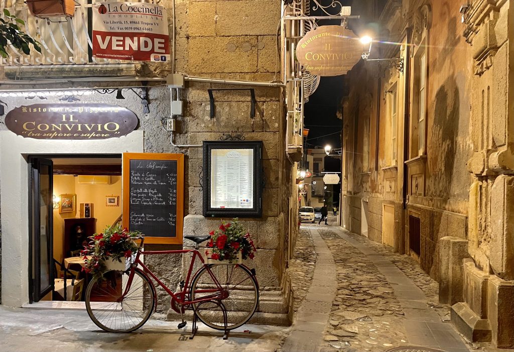 Dark streets in an Italian old town at night, a bike parked in front of a restaurant.