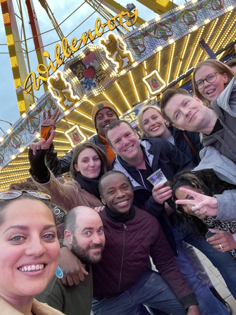 Kate and a group of friends taking a selfie in front of a ferris wheel.