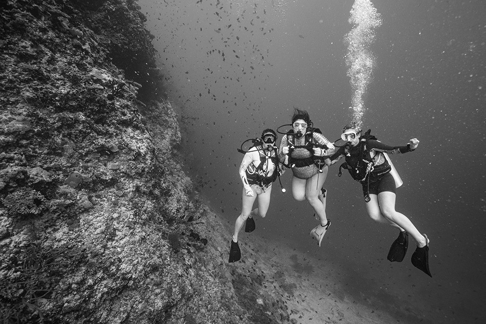 Tres buzos posan bajo el mar, imagen en blanco y negro, Maldivas