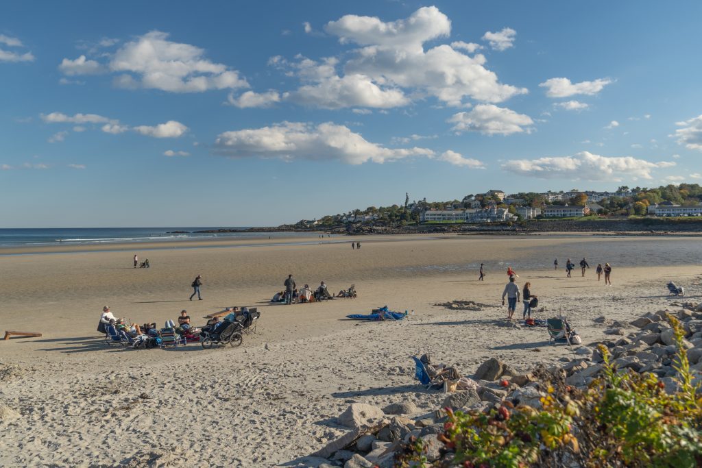 People relaxing on the beach in the fall, wearing light jackets.