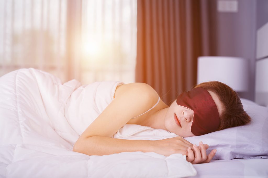 A woman sleeping with a face mask on.