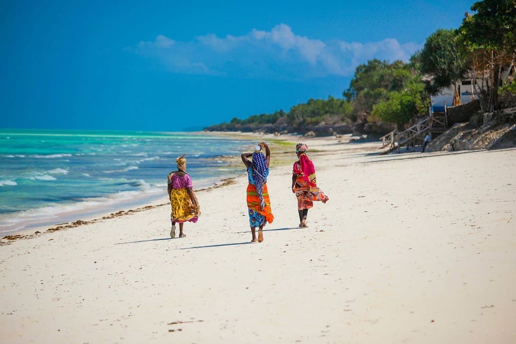 Tres mujeres locales caminando por la playa de Zanzíbar