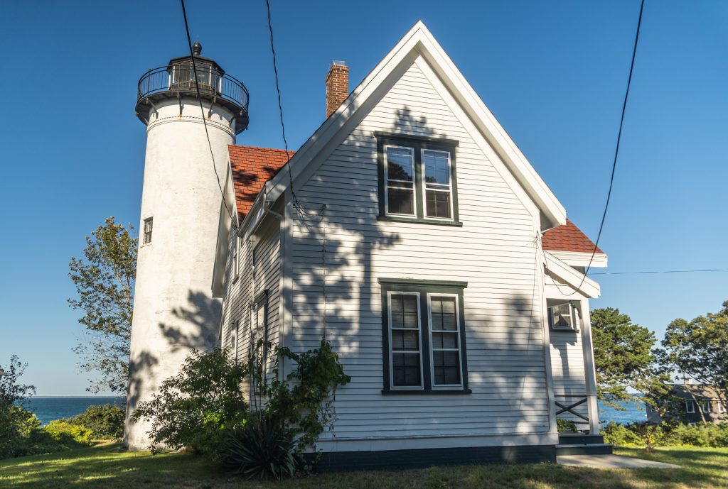 A two-story white house attached to a white lighthouse.