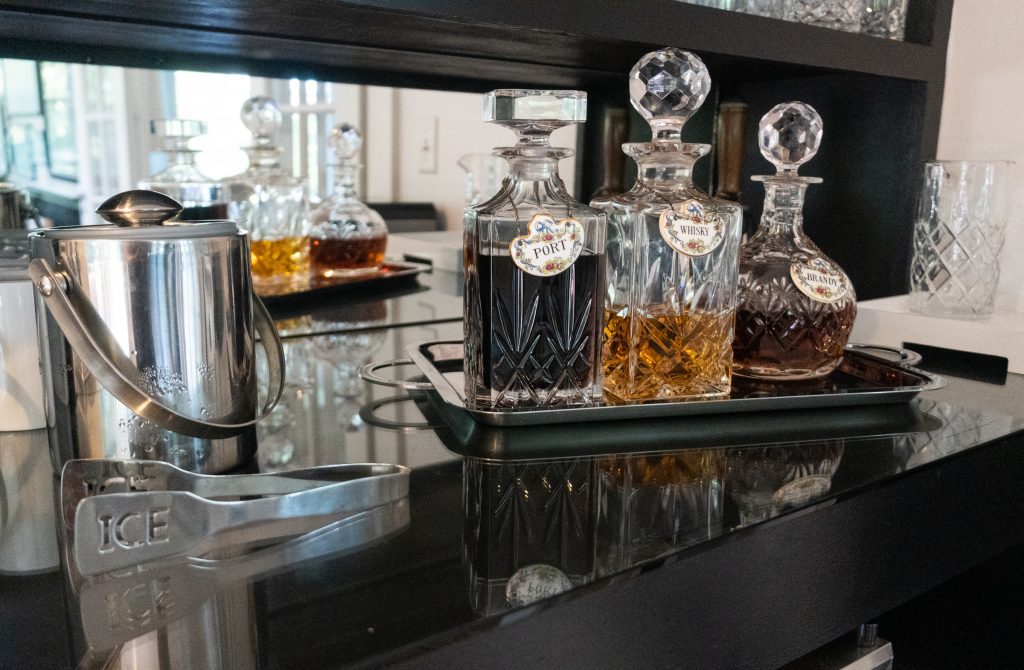 Three crystal bottles of port, whiskey, and brandy sitting on a counter.